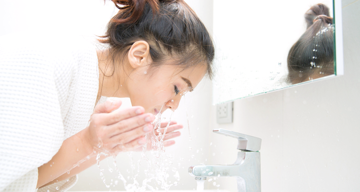 洗面台で顔を洗う女性