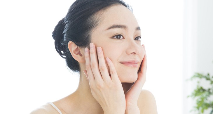 部屋の中で頬をさわる笑顔の女性